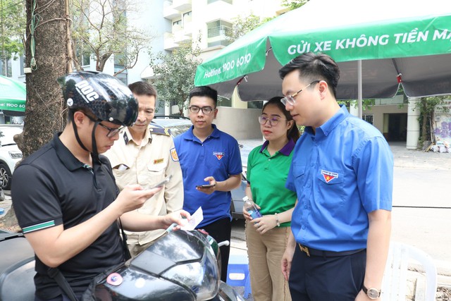 Anh Trần Quang Hưng, Phó bí thư Thành đoàn Hà Nội, và đoàn viên, thanh niên hướng dẫn người dân thanh toán tiền gửi xe không dùng tiền mặt