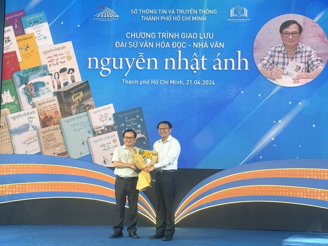 Ông Lâm Đình Thắng - Giám đốc Sở TT-TT TP.HCM (phải) tặng hoa chức mừng nhà văn Nguyễn Nhật Ánh
