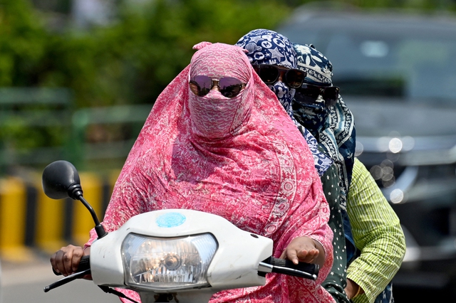 Phụ nữ chống nắng khi đi xe máy tại thành phố Raipur (bang Chhattisgarh, Ấn Độ)
