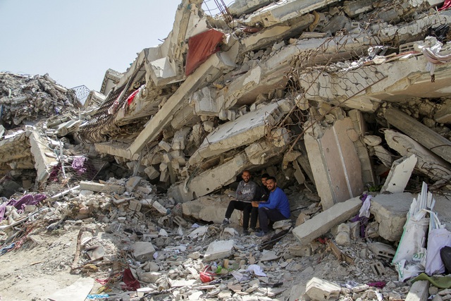 Người Palestine ngày 22.4 ngồi bên đống đổ nát của một tòa nhà dân cư bị phá hủy do các cuộc tấn công của Israel ở phía bắc Dải Gaza