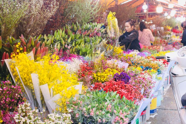 Người bán ở chợ hoa tết Quảng Bá thay bóng đèn compact tiết kiệm điện