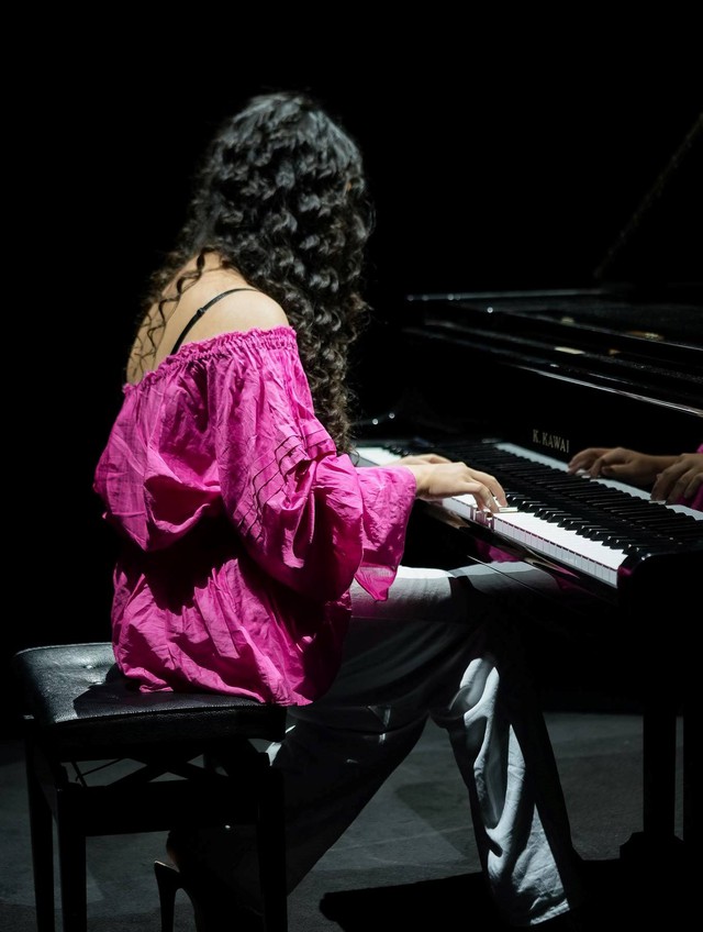 Chiếc áo hồng lệch vai được phối cùng quần lụa đen sang trọng giúp Bella tỏa sáng trên sân khấu với hình ảnh tiểu thư chơi đàn dương cầm