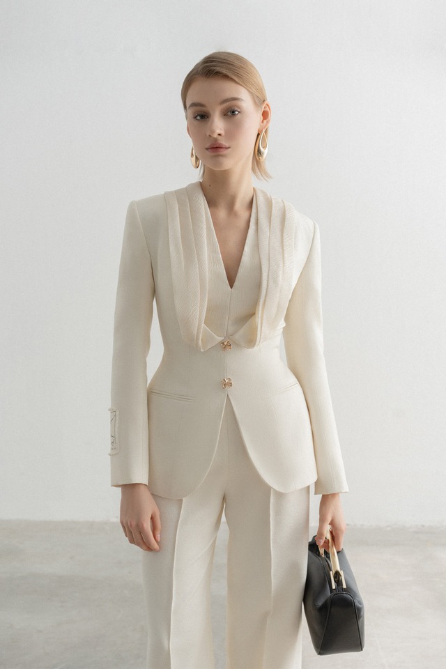 Bộ suit màu trắng kem với những thiết kế không thể thay thế như áo blazer chiết eo có phần cổ cách điệu và quần âu được may đo tỉ mỉ trên nền chất liệu cao cấp sẽ là lựa chọn hoàn hảo cho nàng xuất hiện trong những sự kiện, buổi họp hay buổi tiệc quan trọng