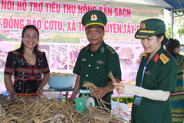 Thiếu tá Nguyễn Đức Vỹ (giữa), Zơ Râm Thị Hiêu (trái) mang thảo dược và nông sản xuống đồng bằng tham gia hội chợ