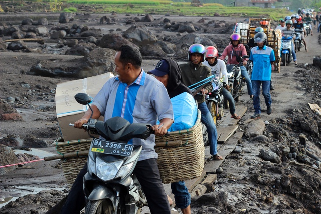 Người dân Indonesia di chuyển qua đoạn đường bị thiệt hại do lũ quét trên đảo Sumatra hôm 14.5