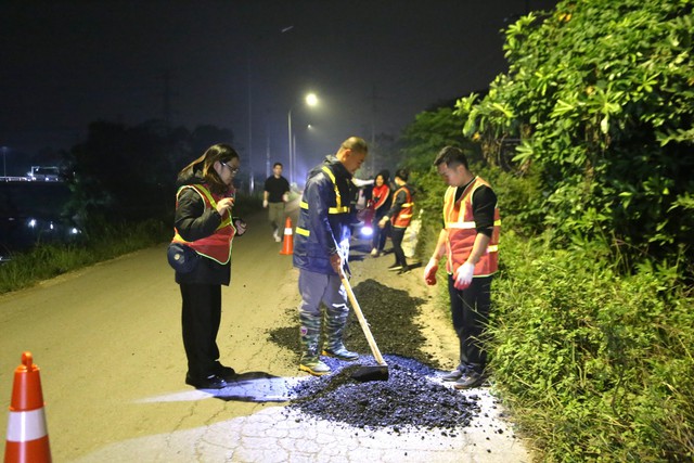 Anh Hiếu (giữa) cùng nhóm vá đường trên tuyến đường ven đê sông Nhuệ qua huyện Thường Tín