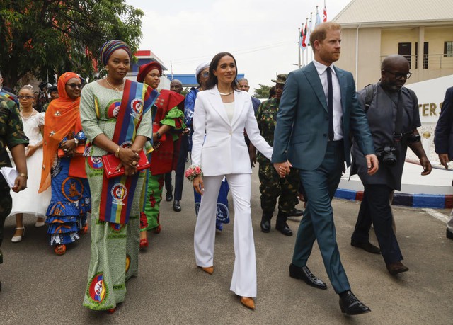 Ngày đầu khi gặp Bộ trưởng Bộ Quốc phòng Nigeria tại Abuja, Meghan mặc bộ trang phục màu trắng của Altuzarra, được thiết kế riêng gồm áo blazer (1.273 bảng) và quần tây (460 bảng). Cựu ngôi sao Suits đi đôi giày da lộn của Manolo Blahnik (595 bảng) và đeo khuyên tai của Ariel Gordon (219,6 bảng)