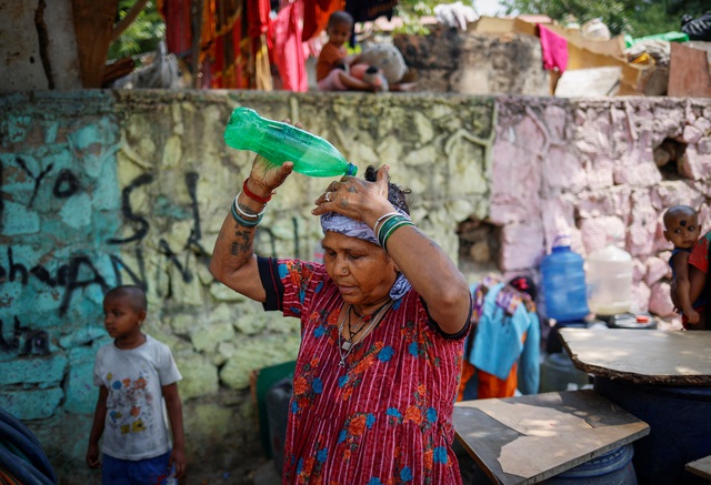 Một người phụ nữ đổ nước lên đầu vào mùa hè nắng nóng ở New Delhi (Ấn Độ) vào ngày 21.5.2024.