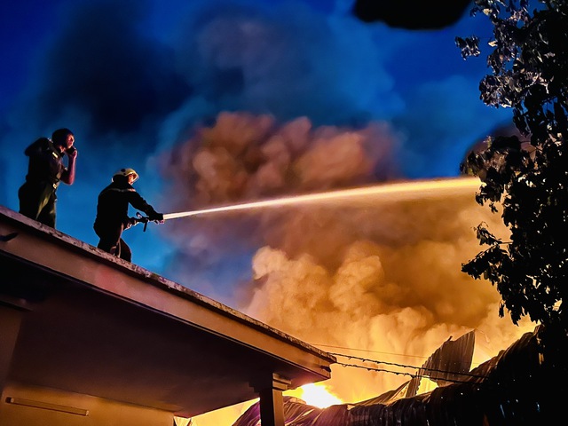 Cảnh sát PCCC phun nước vào đám cháy từ mái nhà dân bên cạnh