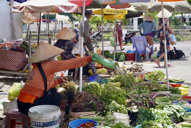 Chị Trần Kim Phương (áo cam), tiểu thương bán rau củ ở chợ Xuân Khánh, trông mưa đến từng ngày để công việc thuận lợi hơn