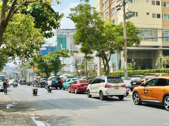 Nhiều ô tô xếp hàng ở sát tim đường chờ di chuyển để nhường đường xe máy đi bên trong