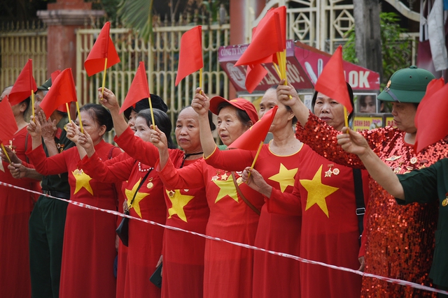 Người dân mặc áo in cờ đỏ sao vàng, hát ca khúc Chiến thắng Điện Biên để cổ vũ