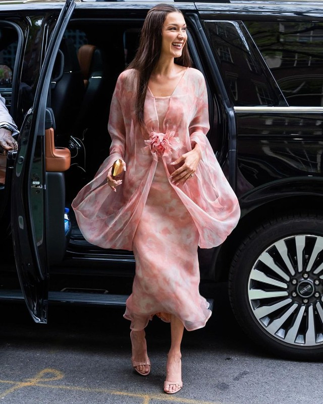 Bella để tóc thả dài tự nhiên khi mặc chiếc váy chiffon họa tiết màu hồng bồng bềnh có cấu trúc phức tạp nối liền tay, vai và điểm nhấn phía thân trước. Thần thái tươi tắn, rạng rỡ của người đẹp 27 tuổi khi đứng giữa vòng vây của fan hâm mộ cho thấy phong độ và đẳng cấp thời trang của siêu mẫu Mỹ