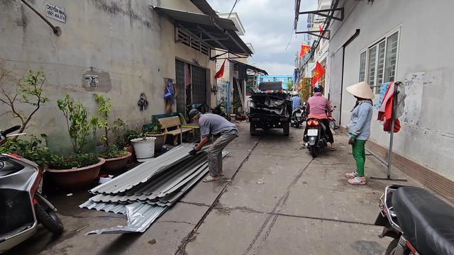 Người dân dọn dẹp các tấm tôn bay trên đường