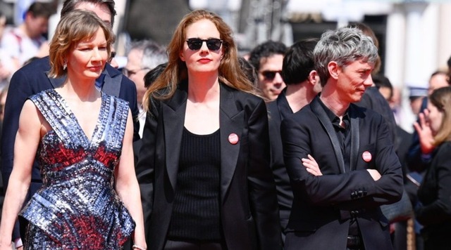Đạo diễn Justine Triet (giữa) và diễn viên Swann Arlaud (phải) đeo huy hiệu Sous les écrans để ủng hộ người lao động làm việc tại LHP Cannes năm ngoái.