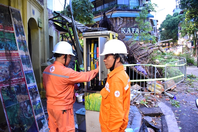 Công nhân EVNHANOI tham gia xử lý sự cố cây đổ, kiểm tra an toàn hệ thống điện ở ngã tư phố Hàng Cá - Chả Cá (Q.Hoàn Kiếm) trong tối ngày 6.9