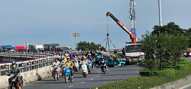 Lật xe taxi c&ocirc;ng nghệ tr&ecirc;n cầu vượt, t&agrave;i xế bị thương, &ugrave;n xe k&eacute;o d&agrave;i - Ảnh 1.