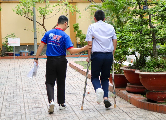 Thí sinh bị gãy chân, di chuyển bằng nạng, được tình nguyện viên tận tình hỗ trợ- Ảnh 3. Thí sinh bị gãy chân, di chuyển bằng nạng, được tình nguyện viên tận tình hỗ trợ- Ảnh 3.