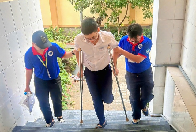 Thí sinh bị gãy chân, di chuyển bằng nạng, được tình nguyện viên tận tình hỗ trợ- Ảnh 1. Thí sinh bị gãy chân, di chuyển bằng nạng, được tình nguyện viên tận tình hỗ trợ- Ảnh 1.