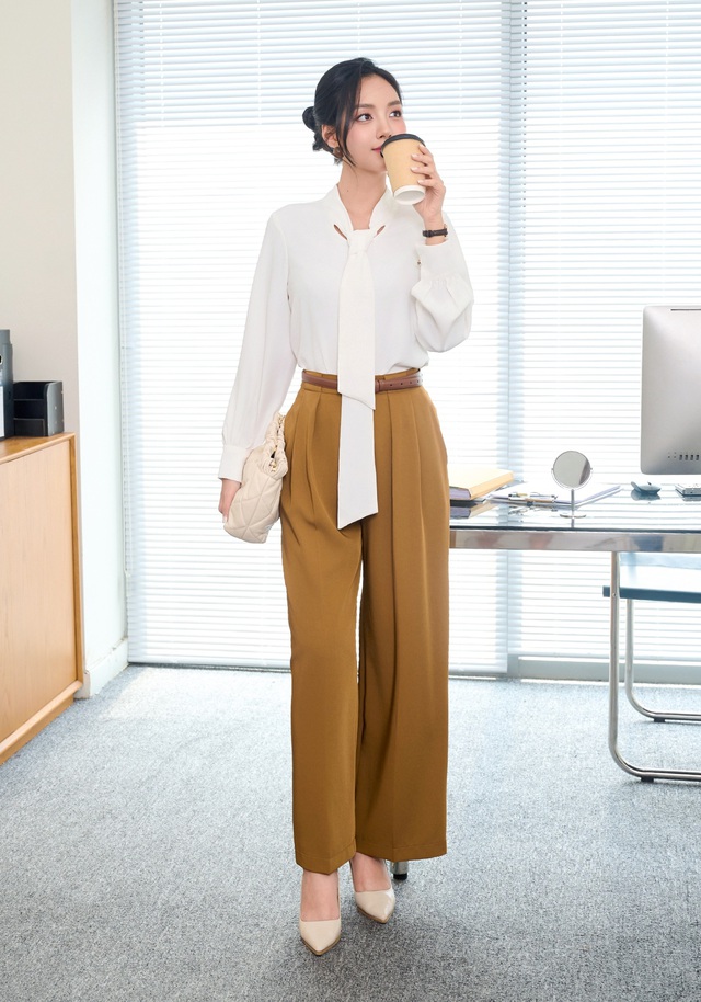 Bộ trang phục với áo sơ mi cổ buộc nơ kết hợp quần ống suông màu nâu đất không chỉ tôn dáng mà còn dễ dàng đồng hành cùng bạn trong nhiều bối cảnh. Bản phối này giúp bạn giữ được phong thái chuyên nghiệp mà vẫn thoải mái, tự tin