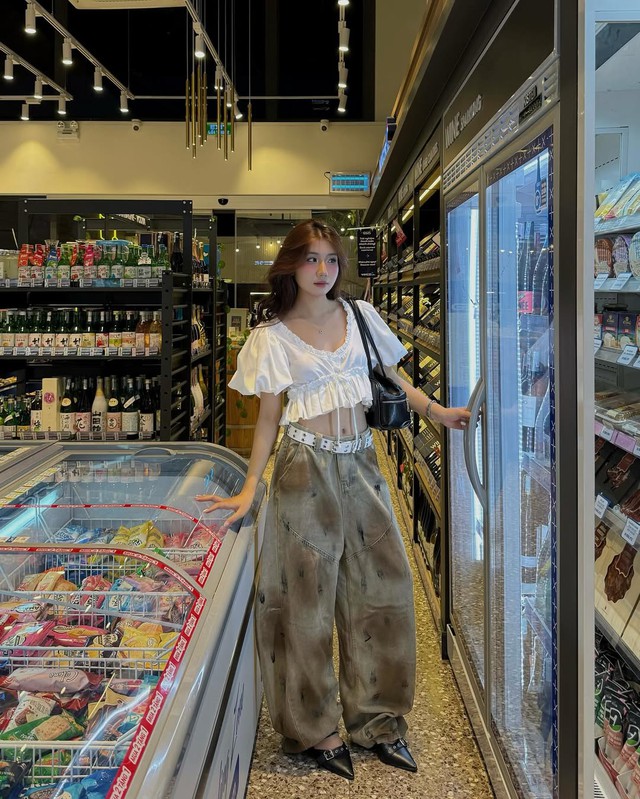 Chiếc áo tay phồng crop top trắng phối cùng quần jeans ống rộng nhuộm loang đã thành công tạo điểm nhấn cá tính đầy mới mẻ. Kết hợp cùng thắt lưng bản to, túi xách đen và giày mũi nhọn, nàng càng trở nên nổi bật hơn dù xuất hiện ở bất cứ nơi đâu