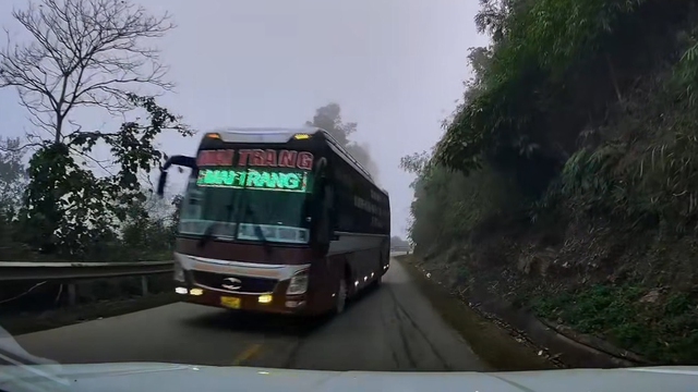 Ô tô con bị xe khách phóng ngược chiều ép vào vách núi - Ảnh 1.