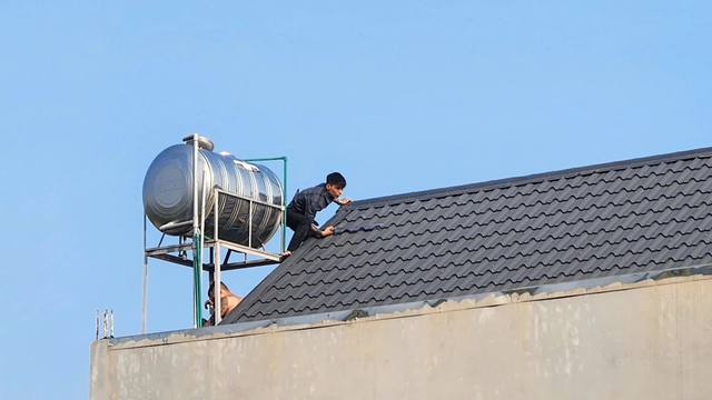 Hai người đàn ông cầm kiếm cố thủ trên mái nhà, công an vây bắt - Ảnh 1.
