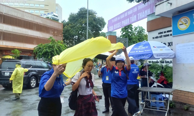 Tình nguyện viên chấp nhận ướt người để giữ khô giấy tờ cho thí sinh - Ảnh 2.