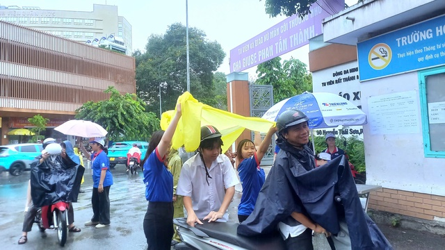 Tình nguyện viên chấp nhận ướt người để giữ khô giấy tờ cho thí sinh - Ảnh 4.