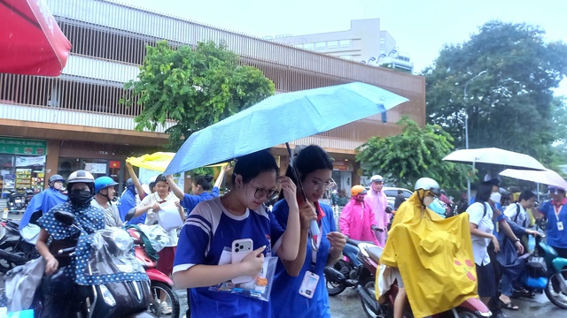 Tình nguyện viên chấp nhận ướt người để giữ khô giấy tờ cho thí sinh - Ảnh 5.