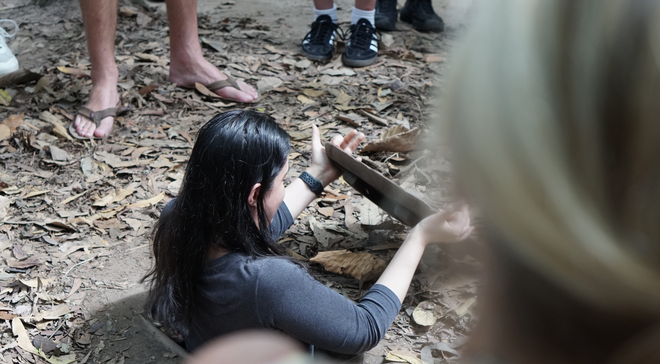 Västerländska turister lyssnar uppmärksamt på guiden som berättar historier vid Cu Chi-tunnlarna - Foto 5.
