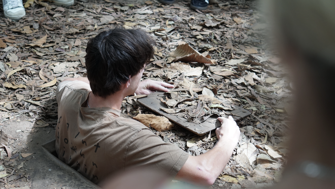 Västerländska turister lyssnar uppmärksamt på guiden som berättar historier vid Cu Chi-tunnlarna - Foto 4.