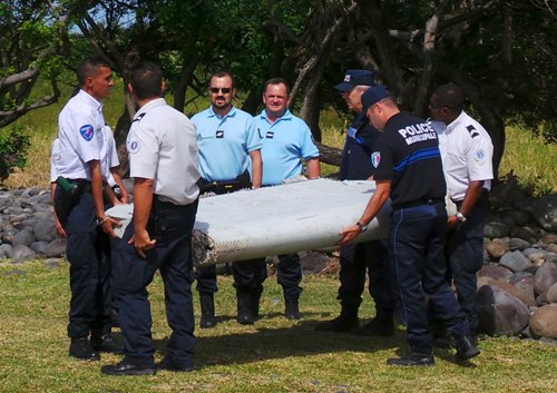 Cảnh sát Pháp khiêng mảnh vỡ máy bay ở bờ biển đảo Reunion - Ảnh: Reuters