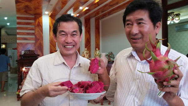 Ông Hiệp (phải) giới thiệu thanh long tím hồng với khách tham quan 