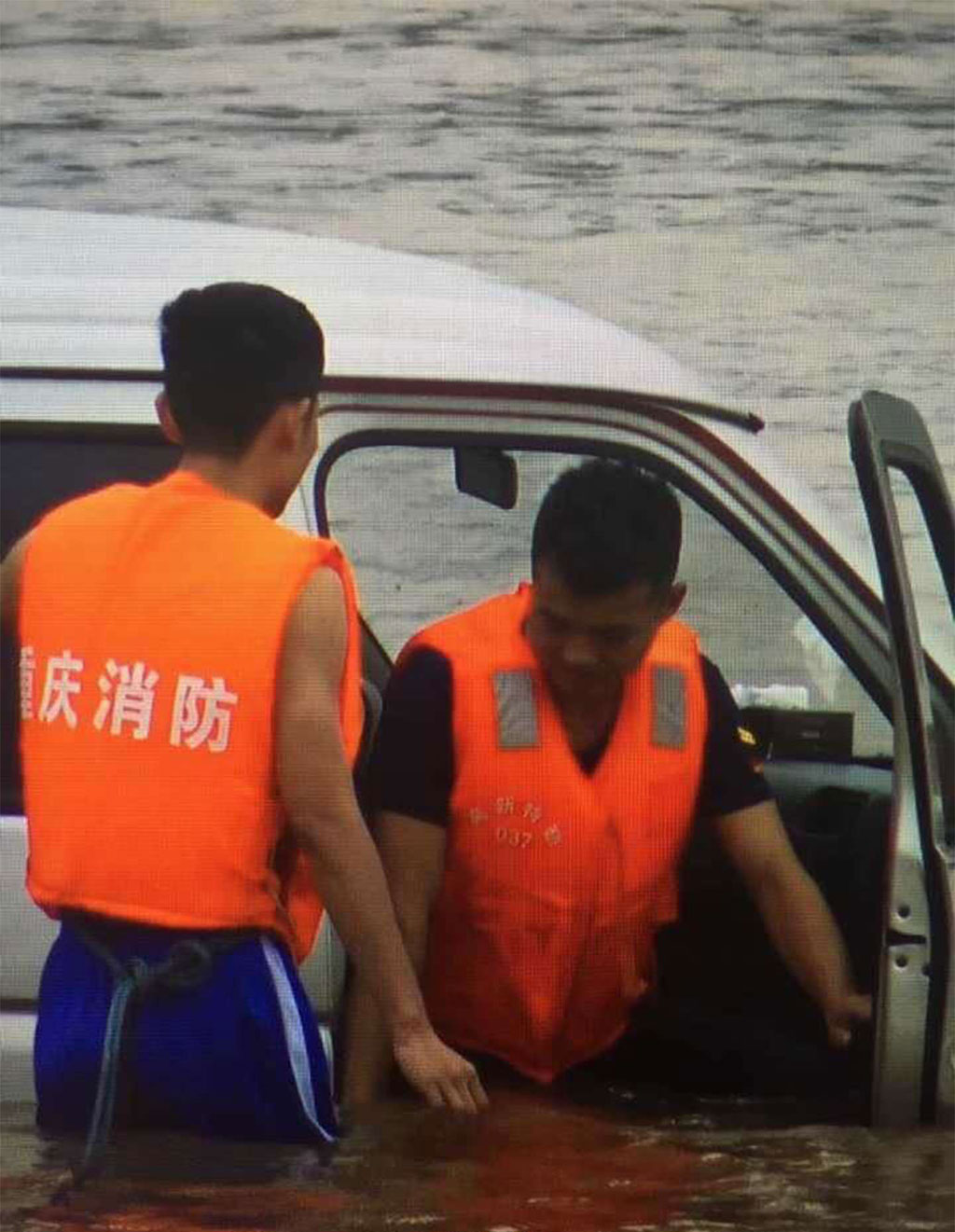 Tài xế Tan (phải) được cảnh sát giải cứu khi nước lũ đã dâng lên thắt lưng. Ảnh: SCMP