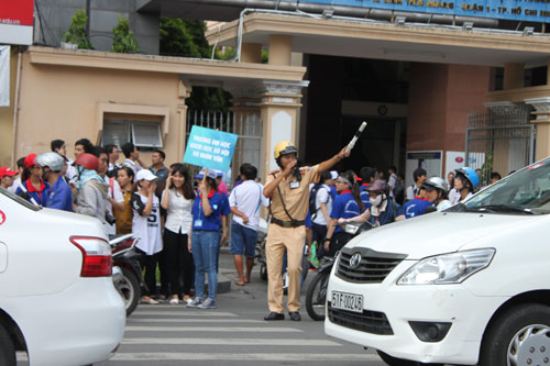 Sinh viên tình nguyện tại điểm thi Trường ĐH Khoa học xã hội và nhân văn TP.HCM (số 10- 12 Đinh Tiên Hoàng, quận 1) đưa thí sinh qua đường sau khi được CSGT điều tiết lưu thông - 3
