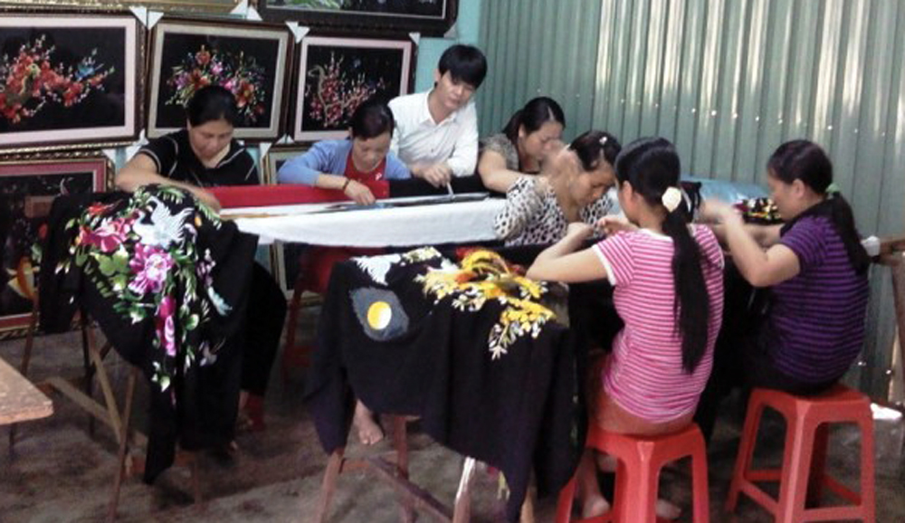 Tùng (áo trắng) đang chỉ dẫn cho thợ thêu tranh