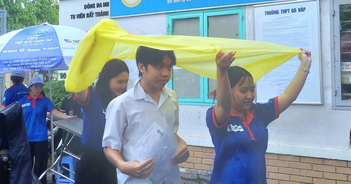 Tình nguyện viên chấp nhận ướt người để giữ khô giấy tờ cho thí sinh