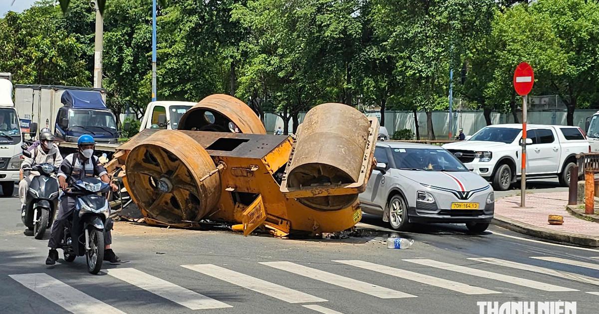 TP.HCM: Xe tải chở xe lu bị lật trên đường, 2 người thoát nạn trong gang tấc