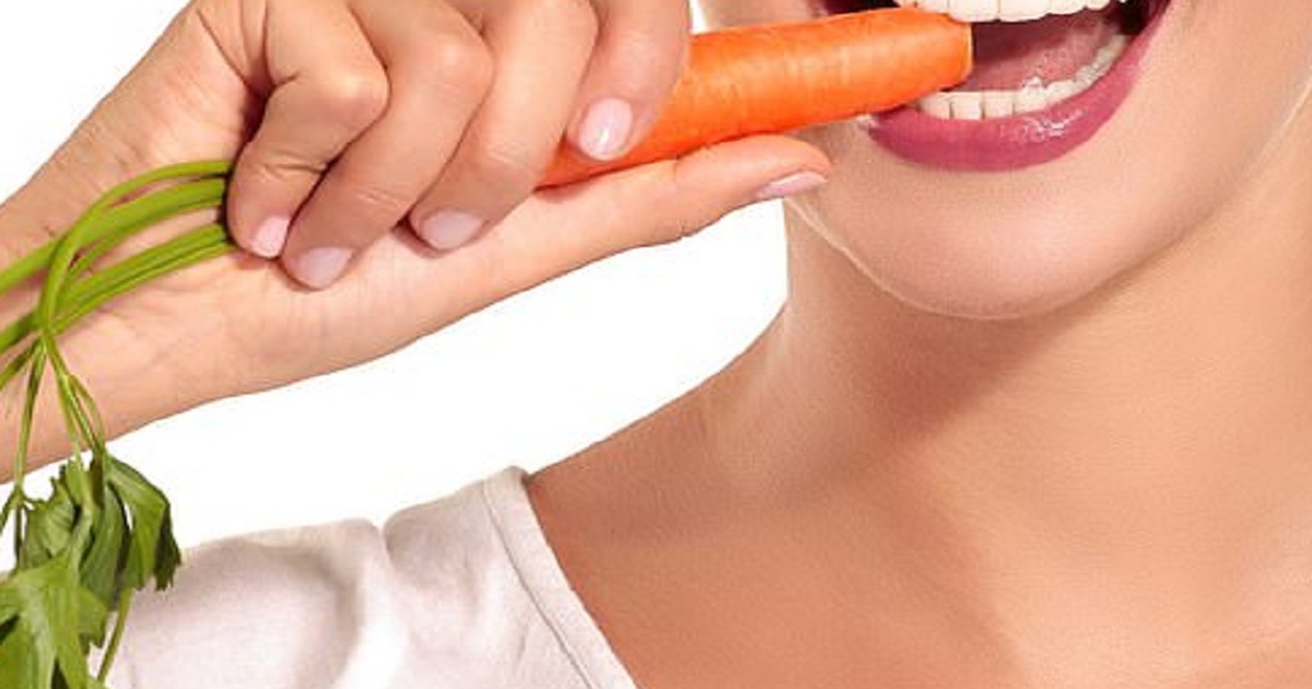 Người cầm cà rốt, chuẩn bị cắn, nền trắng, môi và răng rõ nét.