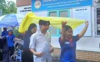 Tình nguyện viên chấp nhận ướt người để giữ khô giấy tờ cho thí sinh