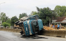 Xe tải chở gỗ lật, đè hai vợ chồng bị thương nặng