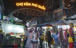 Du khách 'kẹt' ở Phú Quốc tranh thủ che dù, mặc áo mưa đi thăm chợ đêm