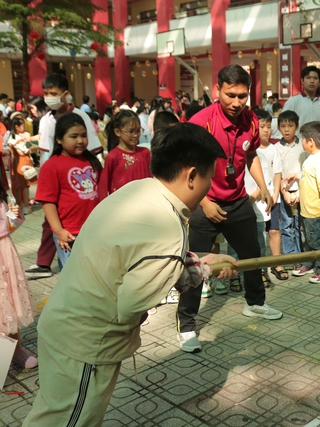 Học sinh chơi đẩy gậy, khắc dưa hấu, làm bánh đón tết ở sân trường