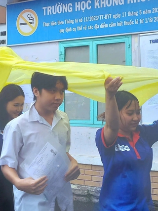 Tình nguyện viên chấp nhận ướt người để giữ khô giấy tờ cho thí sinh
