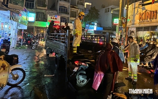 TP.HCM mưa lớn, cây bật gốc: CSGT chuẩn bị xe tải chở xe máy qua vùng ngập