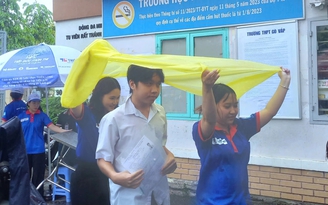 Tình nguyện viên chấp nhận ướt người để giữ khô giấy tờ cho thí sinh
