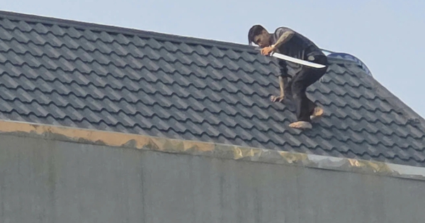 Hai người đàn ông cầm kiếm cố thủ trên mái nhà, công an vây bắt
