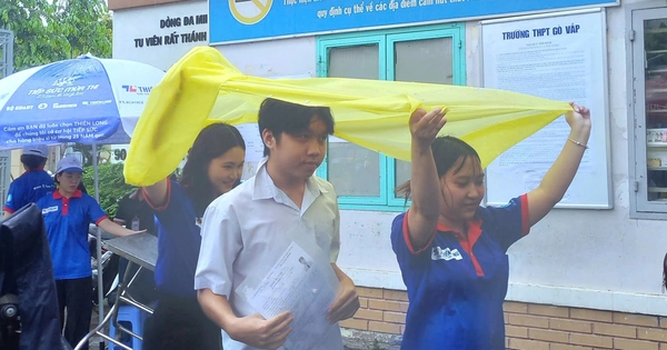 Tình nguyện viên chấp nhận ướt người để giữ khô giấy tờ cho 