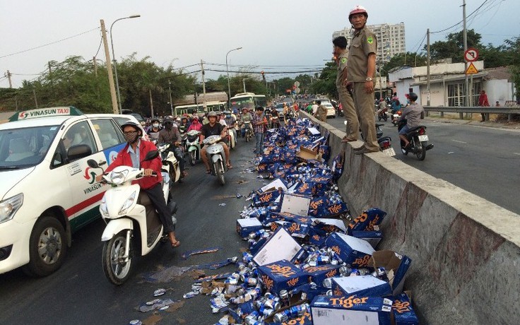 Người dân giúp tài xế gom hàng trăm thùng bia bị đổ xuống đường